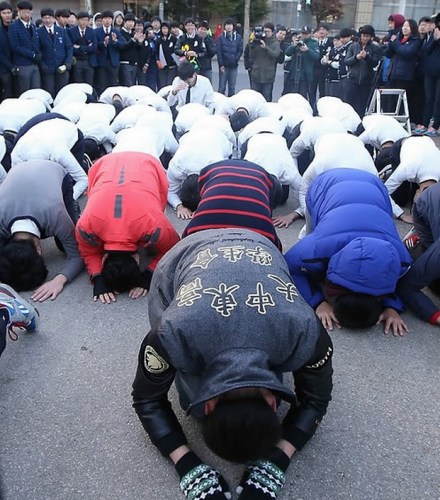 首爾大中高中的低年級學生在寒風中脫下外套，身著白襯衫在考場前下跪行禮，祈禱學長考出高分(網頁截圖)