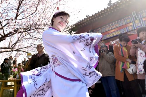 3月23日，一名表演者身著漢服在桃花樹下翩翩起舞。