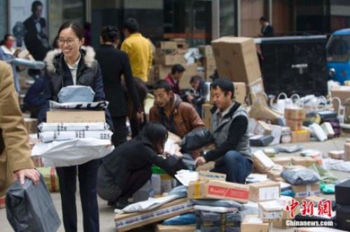 資料圖：隨著&ldquo;雙十一&rdquo;全民網購狂歡節落下帷幕，快遞物流業迎來派送高峰。圖為11月16日，山西太原國貿大廈附近，多家快遞企業的快遞人員在此扎堆分發快遞，一名女白領收到多份快遞十分喜悅。張云 攝