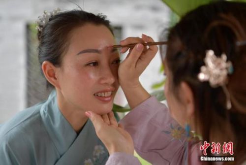 5月29日，四川樂山，漢服愛好者展示端午傳統(tǒng)習(xí)俗&mdash;&mdash;點朱砂。當(dāng)日，一群身著漢服的民眾和慕名而來的游客，穿梭在樂山大佛景區(qū)嘉定坊街頭，他們習(xí)古禮，遙思先賢，感受傳統(tǒng)端午民俗文化。<a target='_blank' >中新社</a>記者 劉忠俊 攝