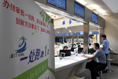 市民在甘肅省玉門市民中心服務大廳窗口辦理業務（2018年8月17日攝）。2017年以來，甘肅省玉門市不斷深化&ldquo;放管服&rdquo;改革，推行&ldquo;一窗辦一網辦簡化辦馬上辦&rdquo;，將當地各部門所有行政審批和公共服務事項向市民中心服務大廳集中，在網絡上向電子政務平臺集中。 