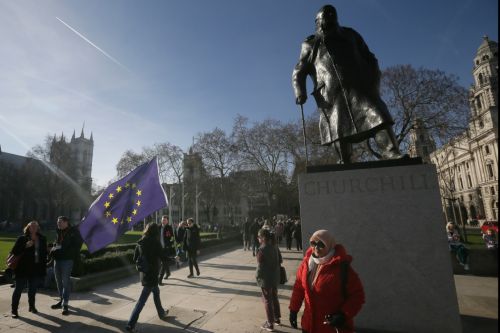 2月14日，在英國倫敦，一名反對&ldquo;脫歐&rdquo;人士手持玫瑰走過丘吉爾的雕像。新華社發(fā)（蒂姆&middot;愛爾蘭攝）